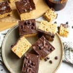 A plate full of rice krispie treats with chocolate.