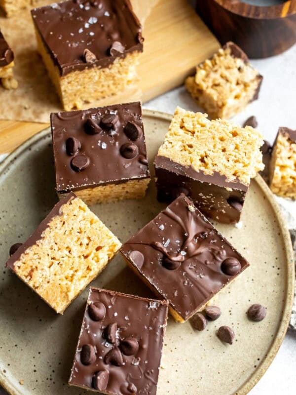 A plate full of rice krispie treats with chocolate.