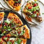 Pizza on a pizza pan and a plate with pizza next to it.