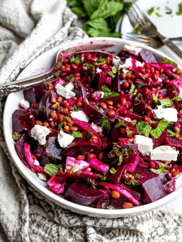 White bowl with beets and feta with a fork.
