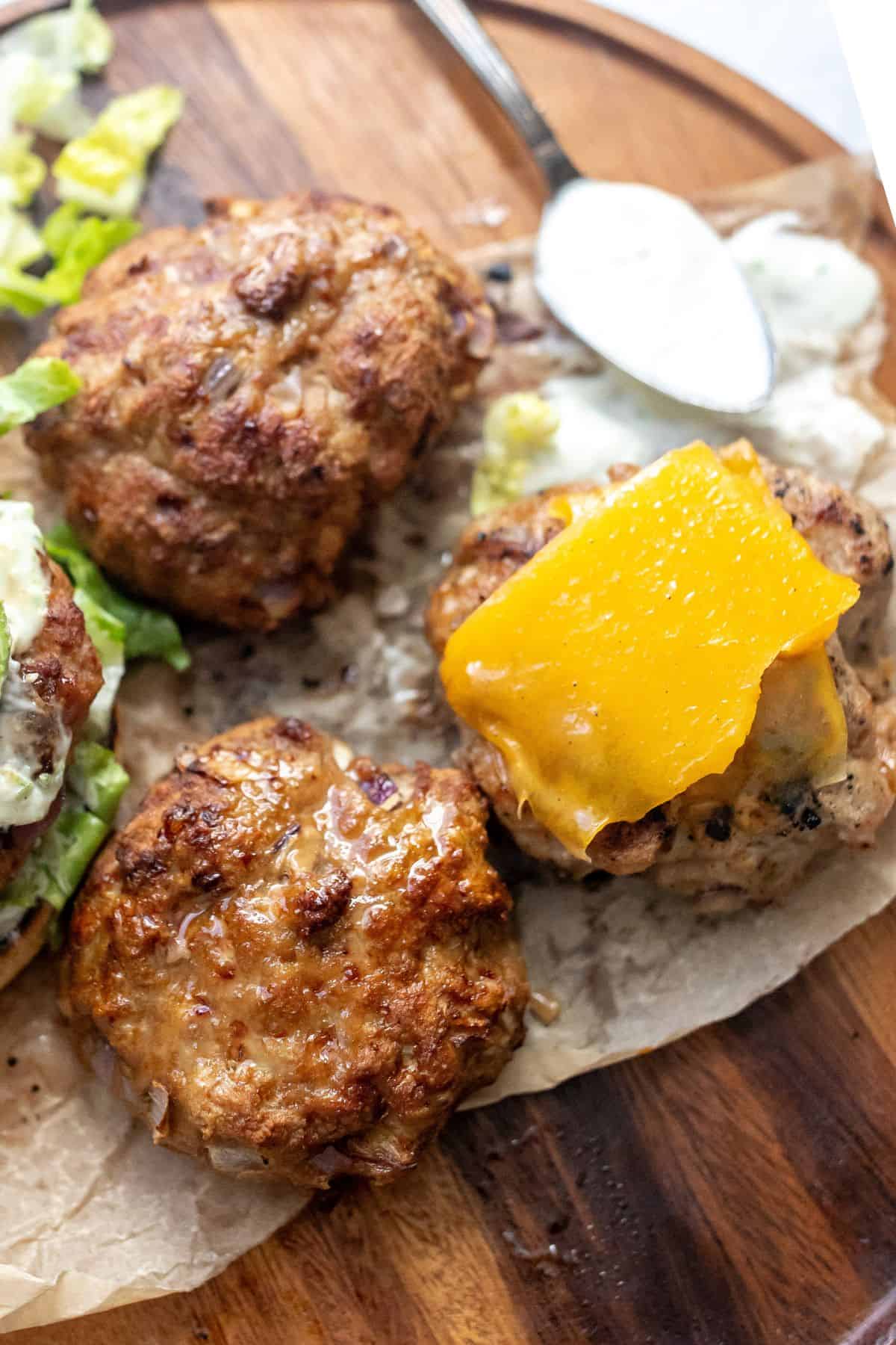 air fried turkey burgers on a wooden plate with a spoon to the side.