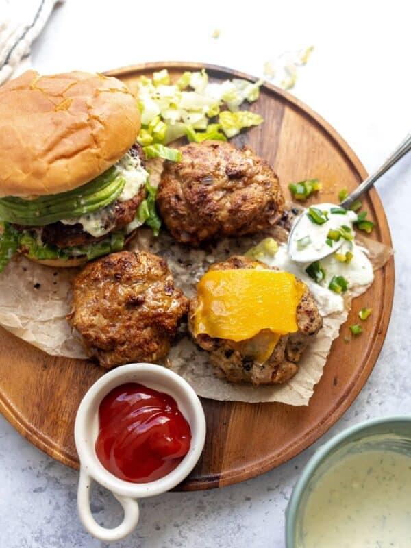 Turkey Burgers on buns on a plate and spoon on the side with jalapeño mayo.