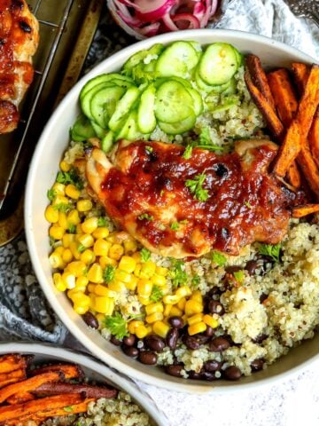 White bowl with bbq chicken thighs and rice and quinoa.