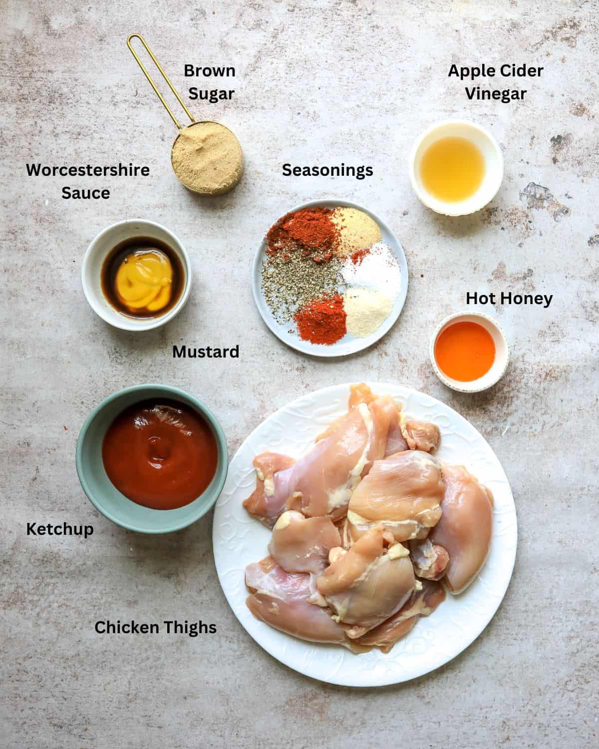 Ingredients needed to make oven bbq chicken thigh recipe on a counter in small bowls and measuring cups.  