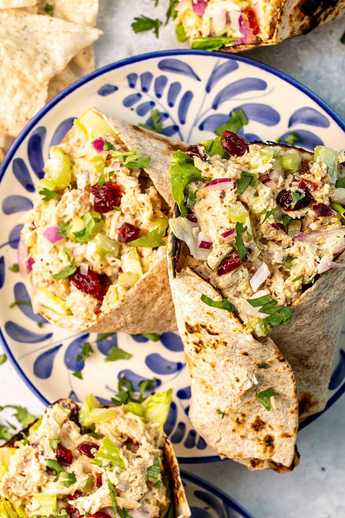 Two chicken salad wraps on a blue and white plate.
