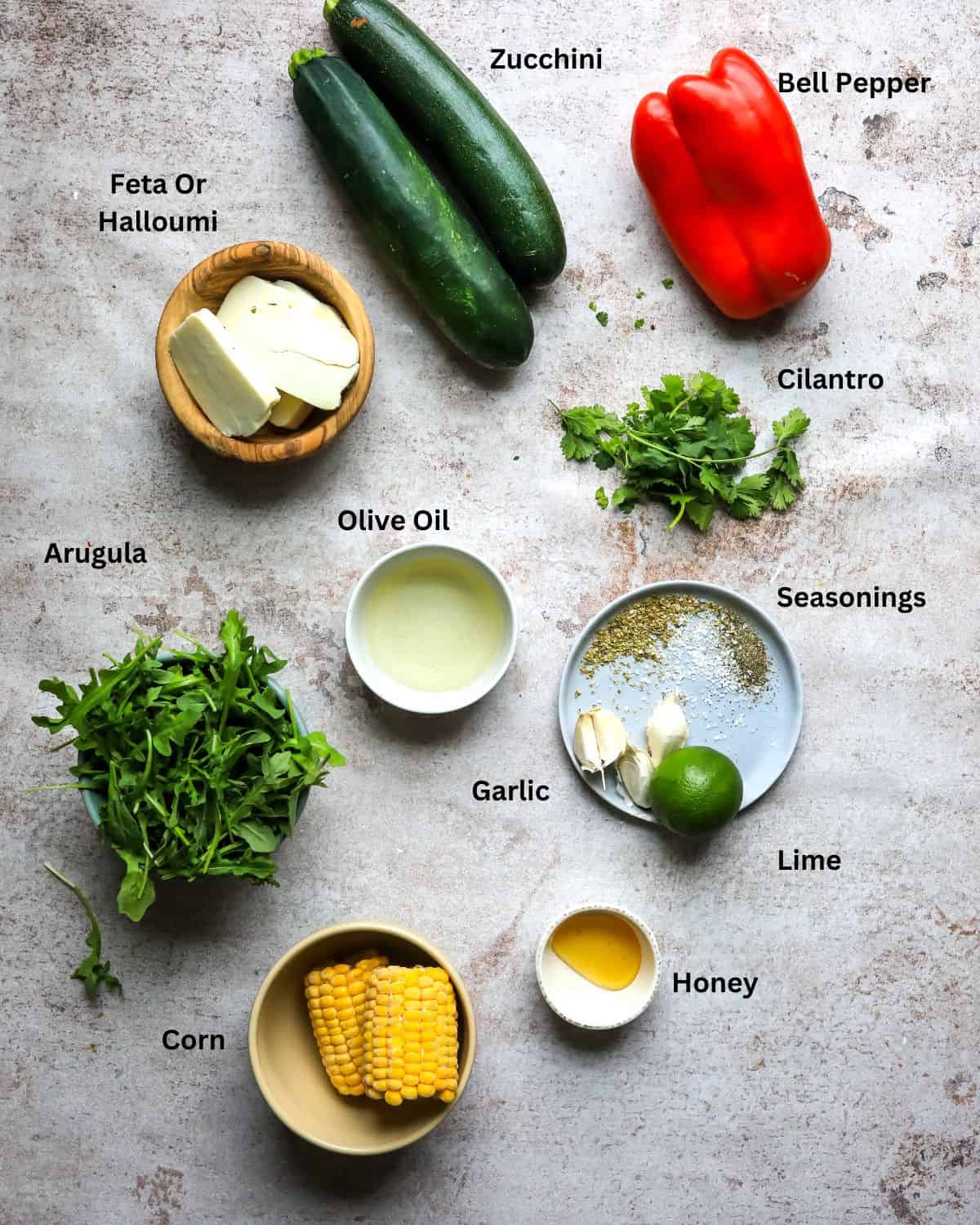 Ingredients needed to make grilled zucchini salad on a counter top. 