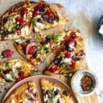 Flatbread with Mediterranean toppings on parchment.