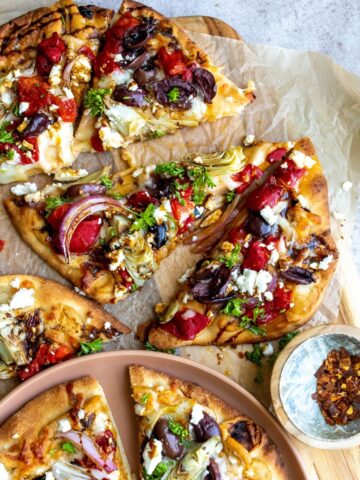 Flatbread with Mediterranean toppings on parchment.