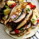 Up close photo of mushroom asada tacos with toppings on a plate.