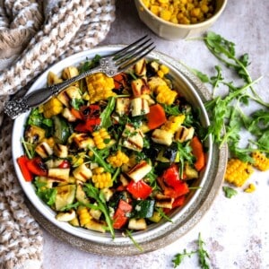 White bowl full of fresh veggie and a silver fork on a counter.