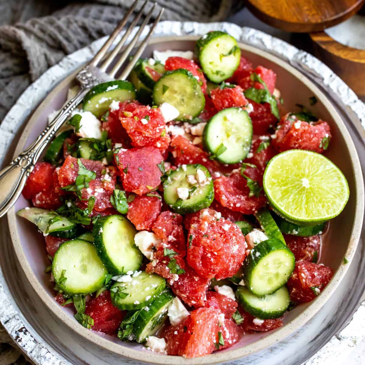 White ceramic bowl with watermelon basil salad in it and a silver fork.