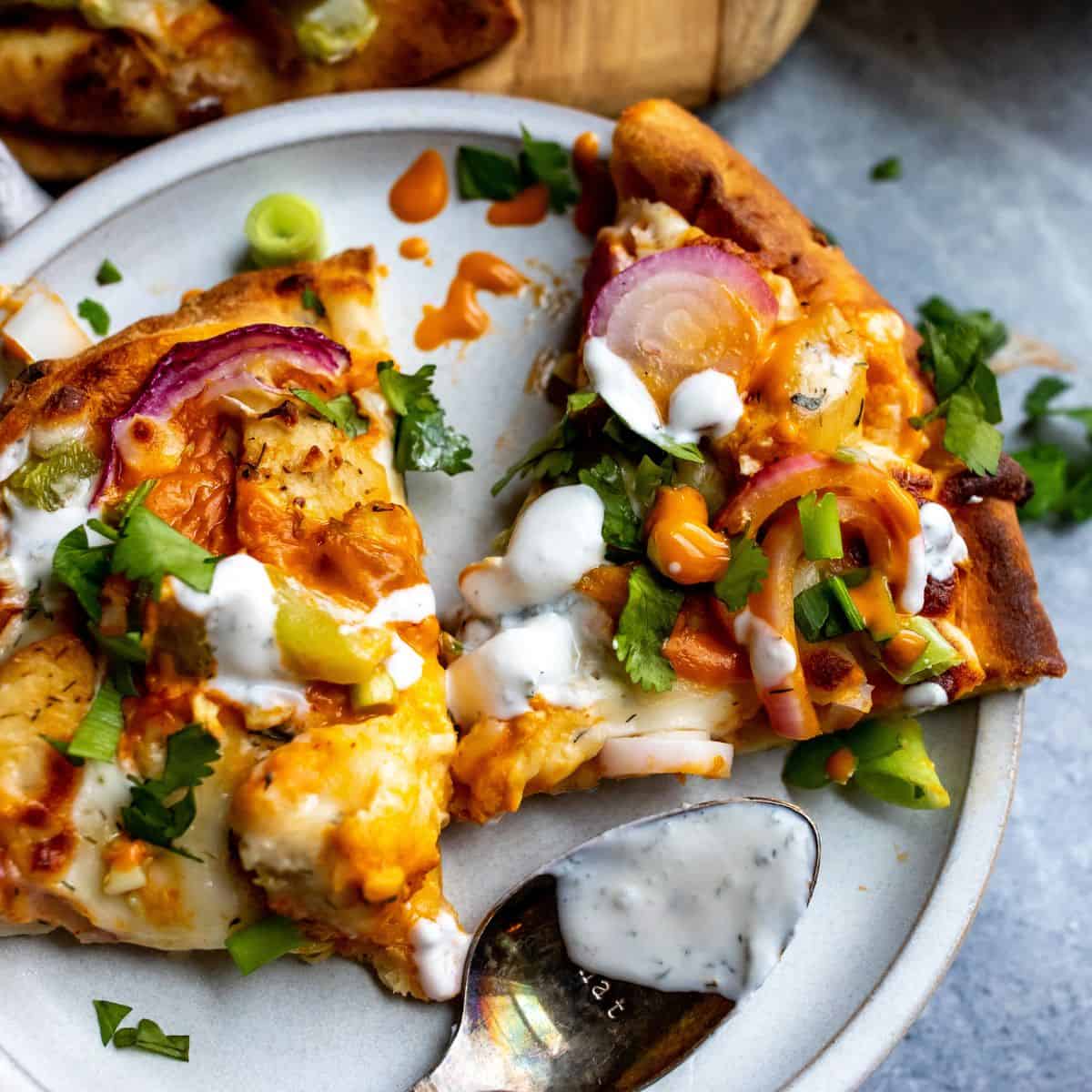 Up close photo of two slices of buffalo chicken flatbread on a white plate. 