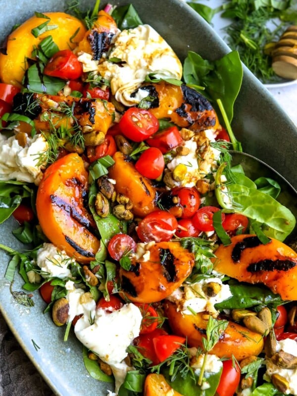 Grilled peaches on greens in a serving platter.