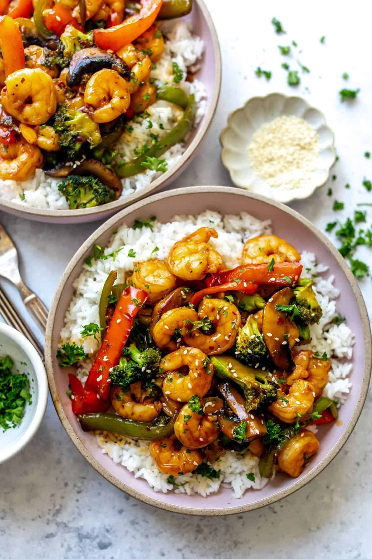 Teriyaki Shrimp and rice in two pink ceramic bowlswith a fork.