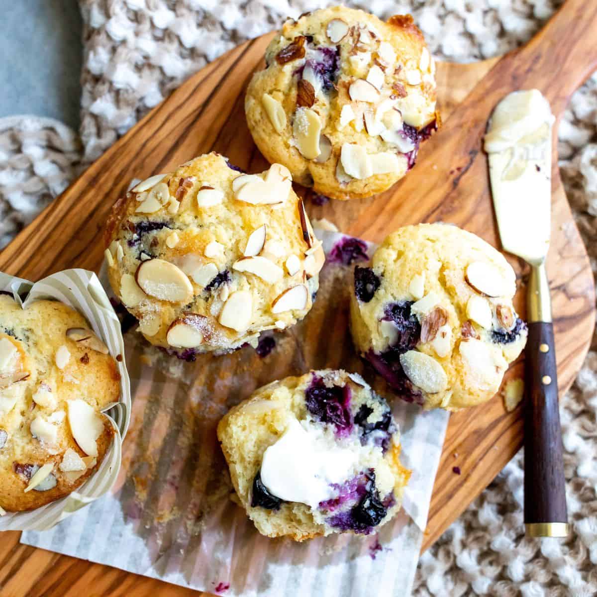 Blueberry yogurt muffins on a cutting board with a knife.