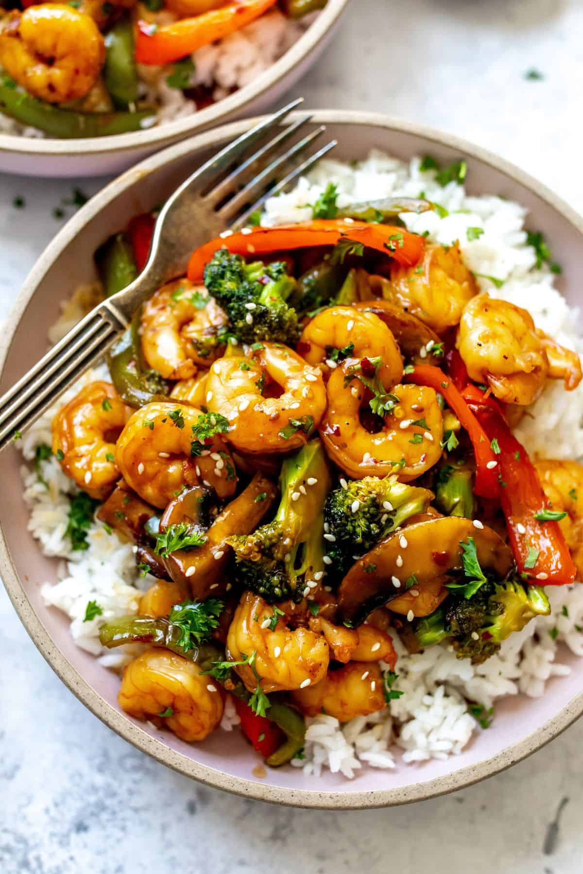 Teriyaki Shrimp and rice in a pink ceramic bowl with a fork.