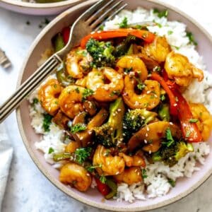 Teriyaki Shrimp and rice in a pink ceramic bowl with a fork.