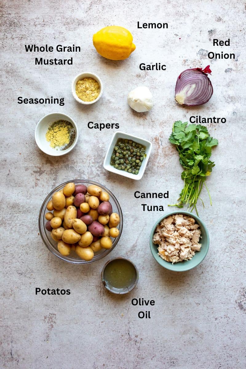 Ingredients needed to make this tuna potato salad on a counter with small bowls. 