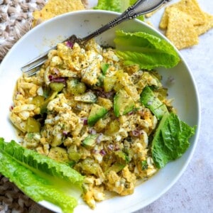 White bowl with egg and avocado mix in it and lettuce.