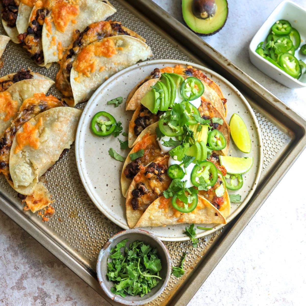 Crispy black bean tacos on a white ceramic plate with toppings and limes. 
