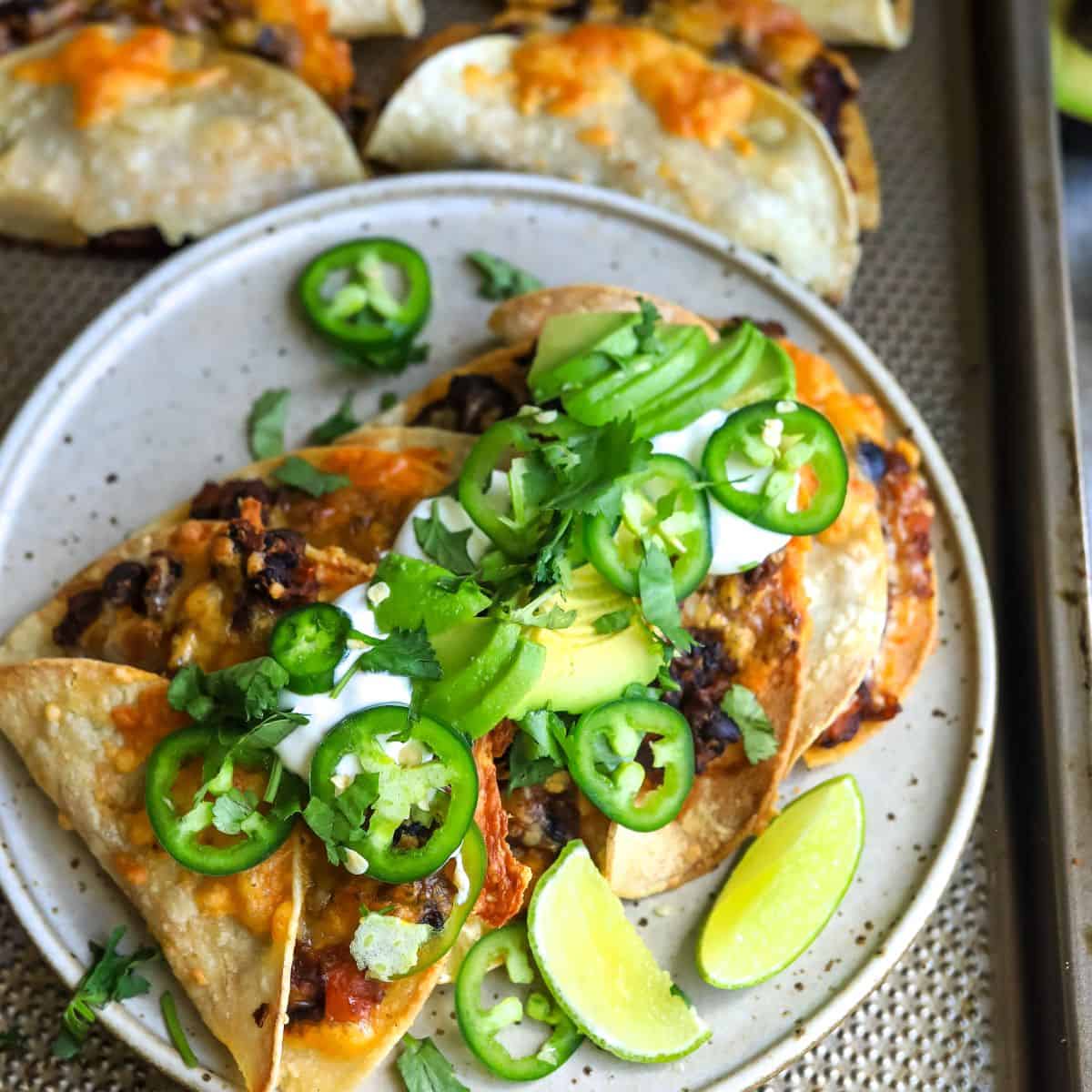 Crispy bean tacos up close on a plate with toppings.