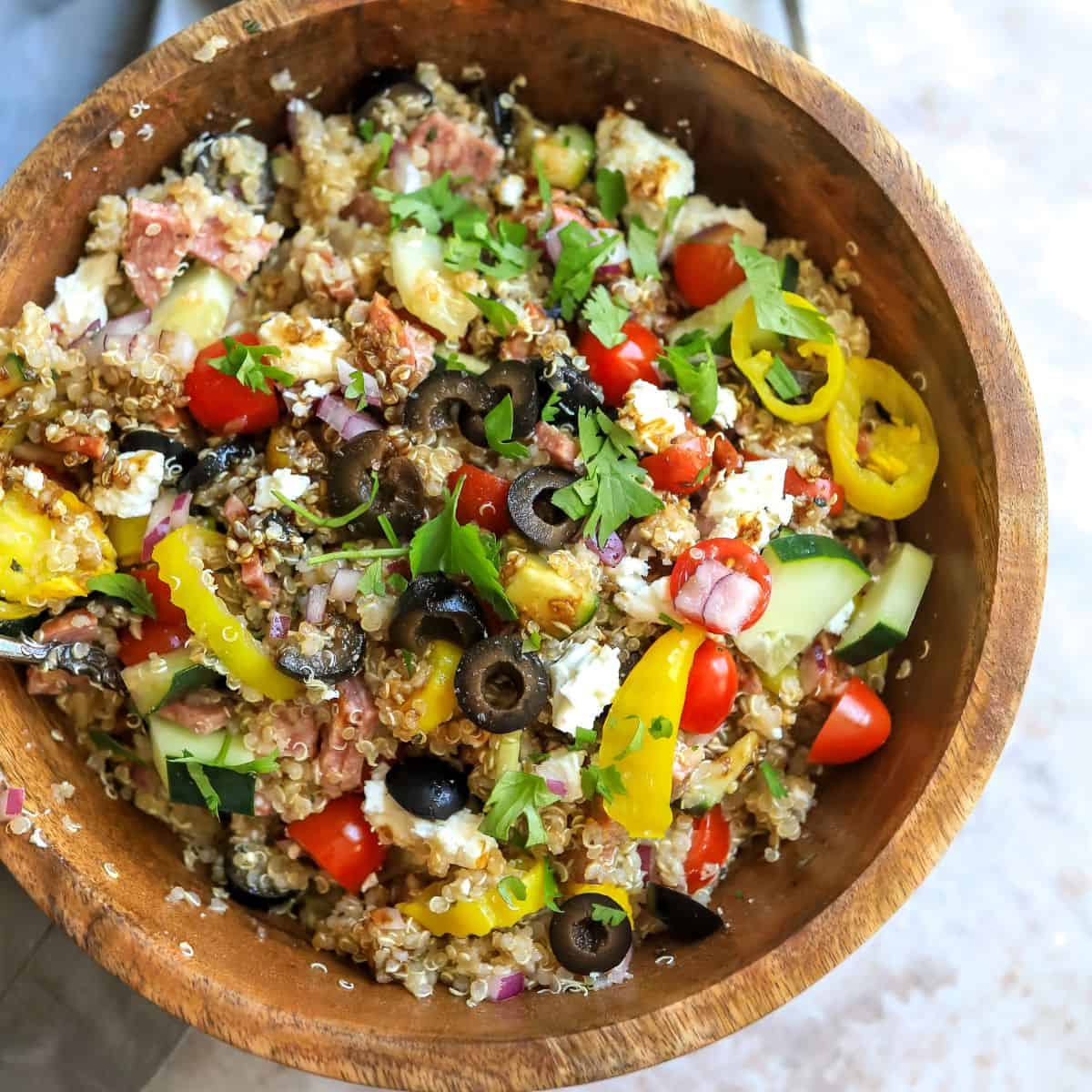 Large wooden bowl with Italian quinoa salad with veggies. 