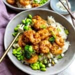 Mongolian shrimp in a grey bowl with edamame and a gold fork.