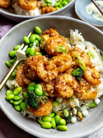 Mongolian shrimp in a grey bowl with edamame and a gold fork.