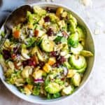 White ceramic bowl with brussel sprout salad in it and silver spoon.