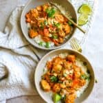 Two bowls with rice and chicken satay and limes.