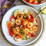Sweet Chili Shrimp in a white bowl with peppers and sauce in it served over rice.