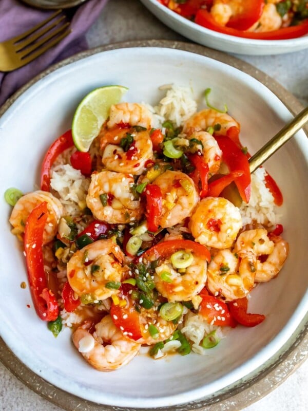 Sweet Chili Shrimp in a white bowl with peppers and sauce in it served over rice.