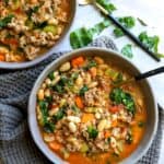 Grey bowl with black spoon and tuscan white bean soup in it.