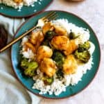 Green plate with rice and chicken and broccoli. Gold fork in the chicken.