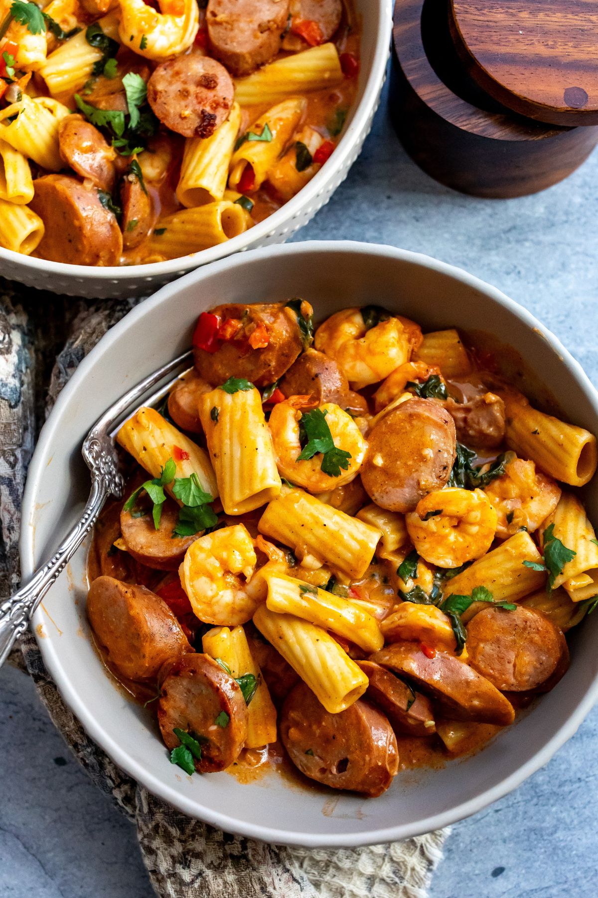 Grey bowls with texture on them. Filled with pasta, sausage and shrimp.