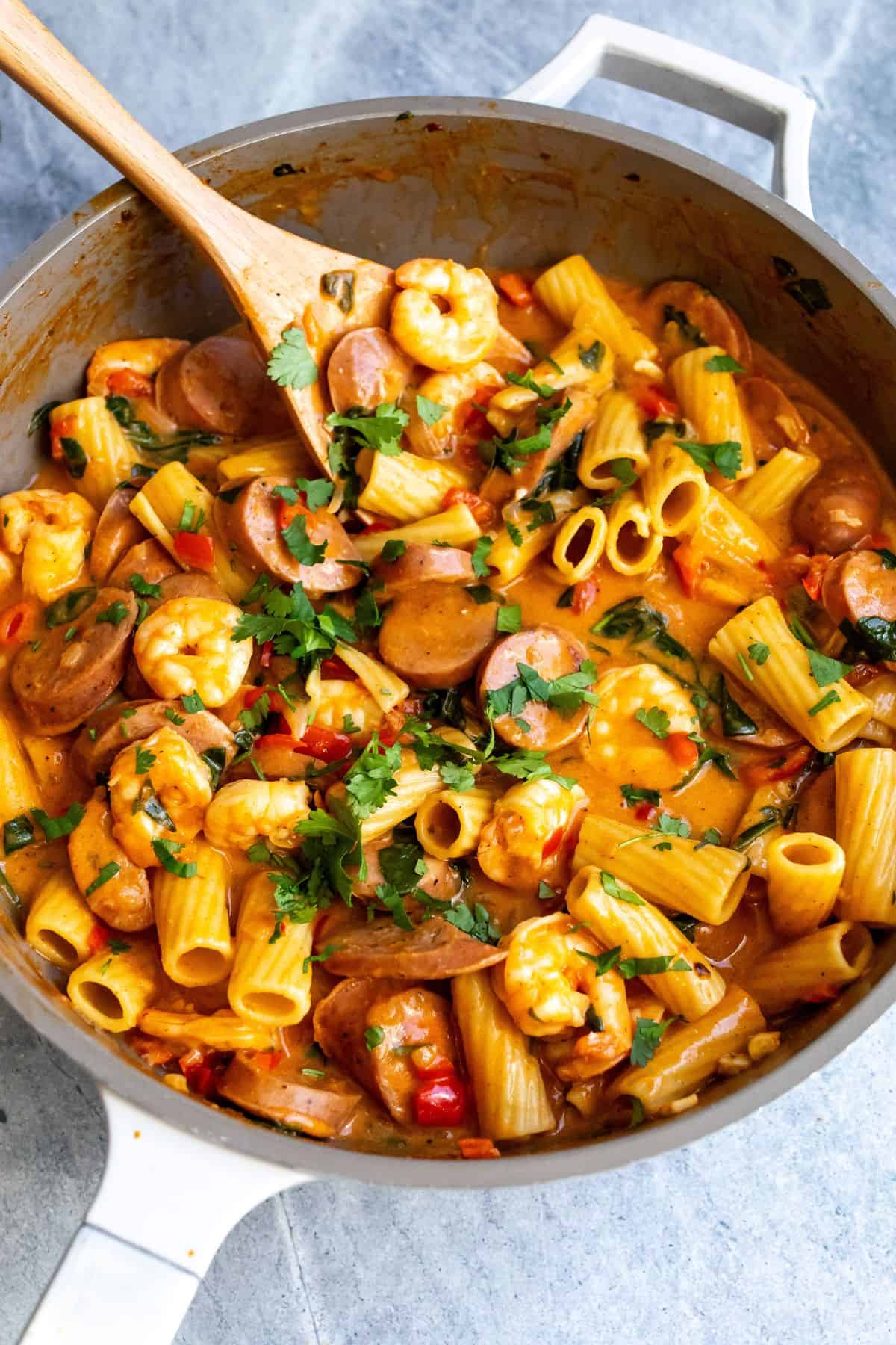 Skillet filled with pasta, sausage and shrimp.