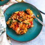 Green ceramic plate with brown rims. Casserole on the plates garnished in basil and cheese.