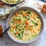 Grey bowls with creamy soup and veggies in it, a gold and black spoon.