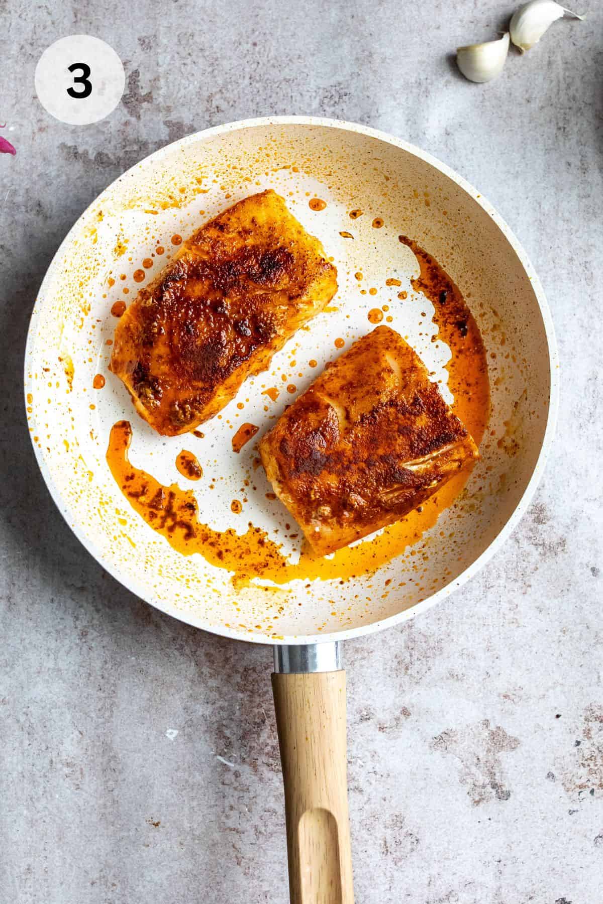 Fish in a skillet with seasoning.