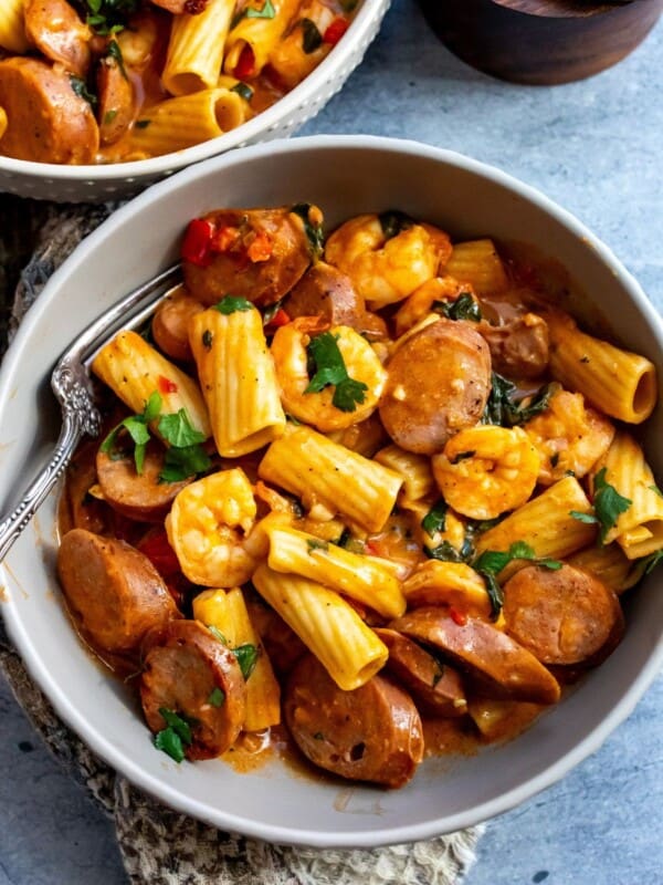 Grey bowls with texture on them. Filled with pasta, sausage and shrimp.