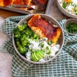 Grey bowl on a green towel with coconut rice and salmon in the bowl.