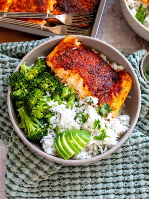 Grey bowl on a green towel with coconut rice and salmon in the bowl.