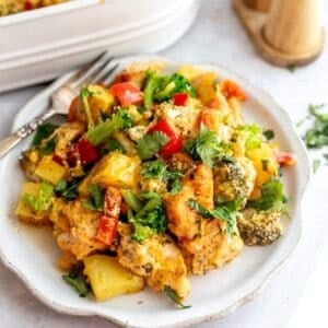white plate with chicken broccoli potato casserole on it and a fork.