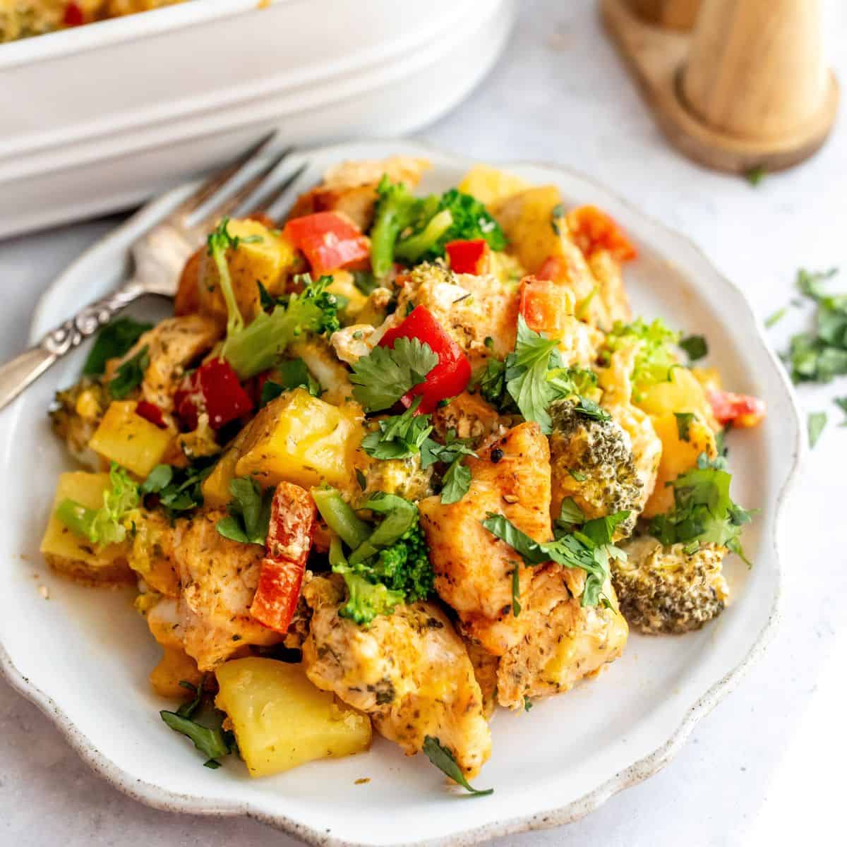 white plate with chicken broccoli potato casserole on it and a fork.