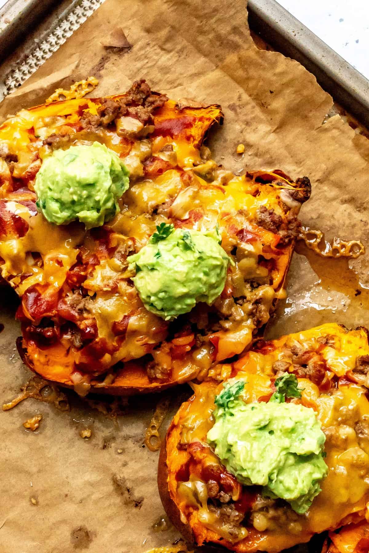 Stuffed Sweet Potatoes on a baking sheet with melted cheese.