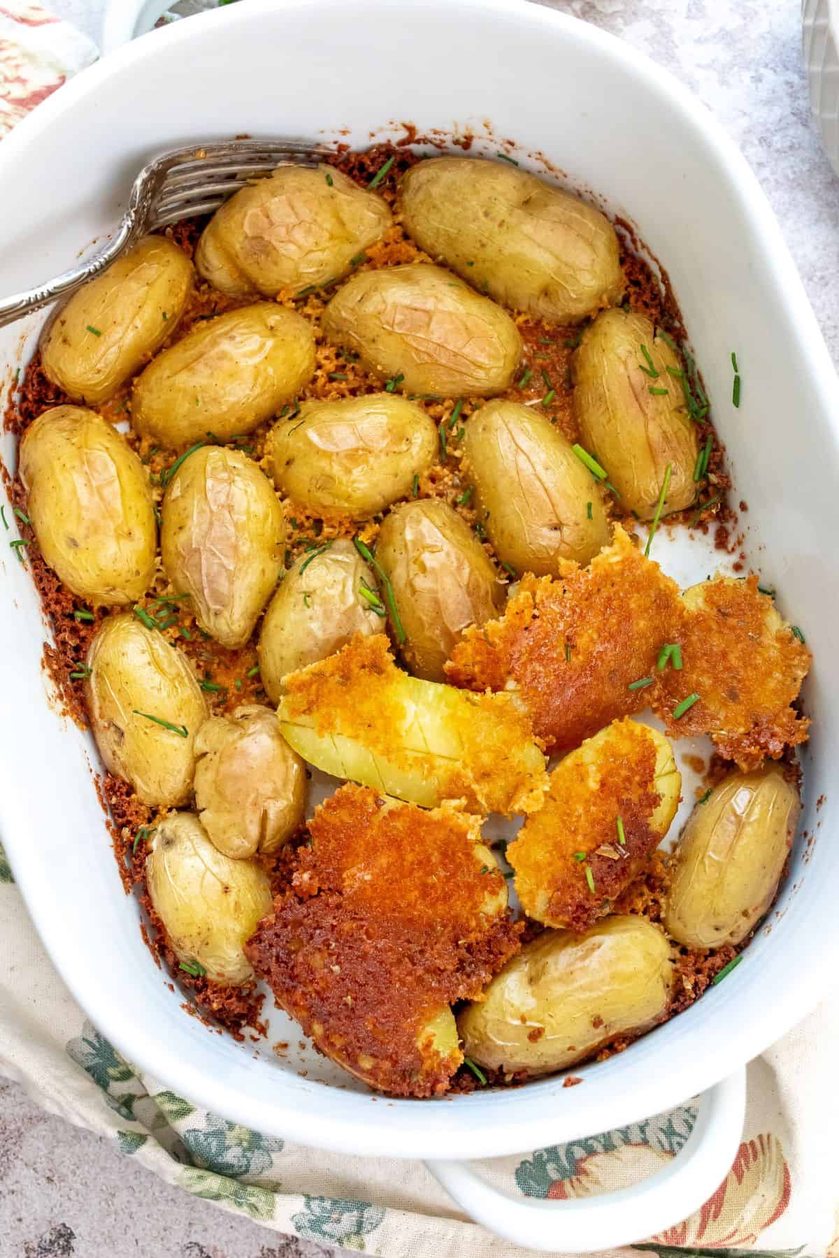 Parmesan crusted around potatoes in a white baking dish. 