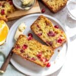 White plate with cranberry orange bread and a butter knife to the side.