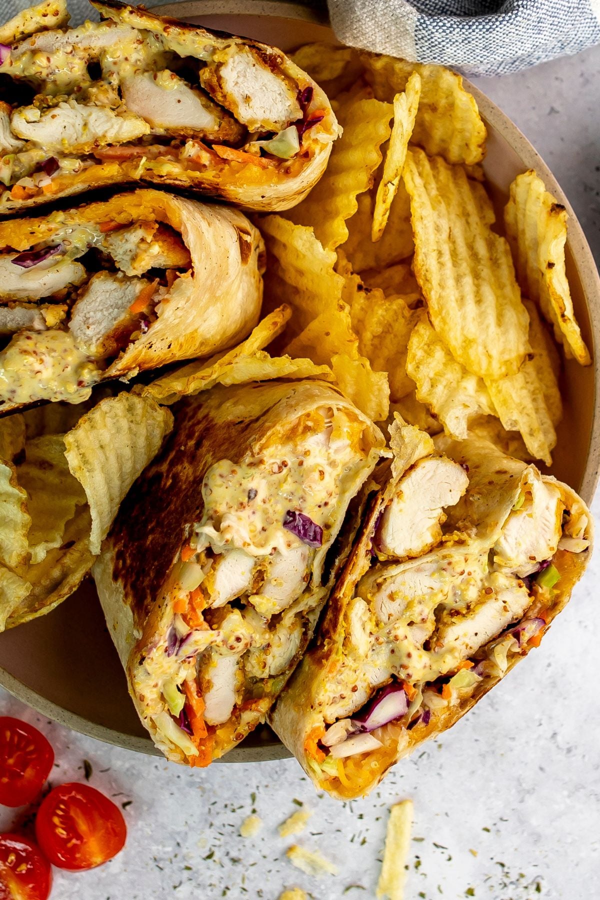 Honey Mustard Chicken wraps in a ceramic bowl with chips on the side.