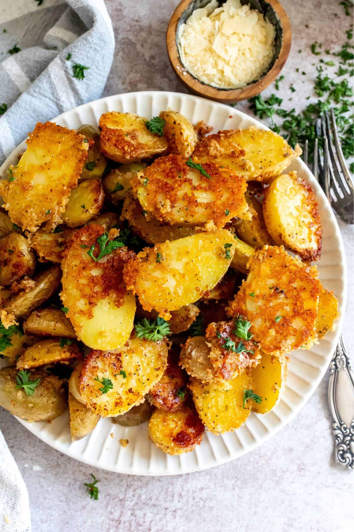 Grey bowl with parmesan potatoes and a silver fork. 