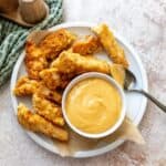 Spicy mustard with honey and seasonings in a bowl with chicken on the side.
